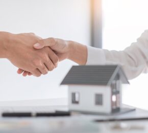 Estate agent in suit sitting in an office desk shaking hands with customer after contract signature accept agreement finish buying or rental real estate for transfer right of property